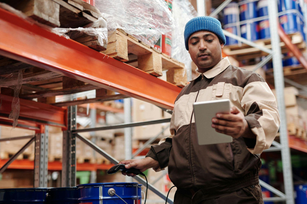 Logistics worker using a tablet and scanner to manage inventory in a warehouse.